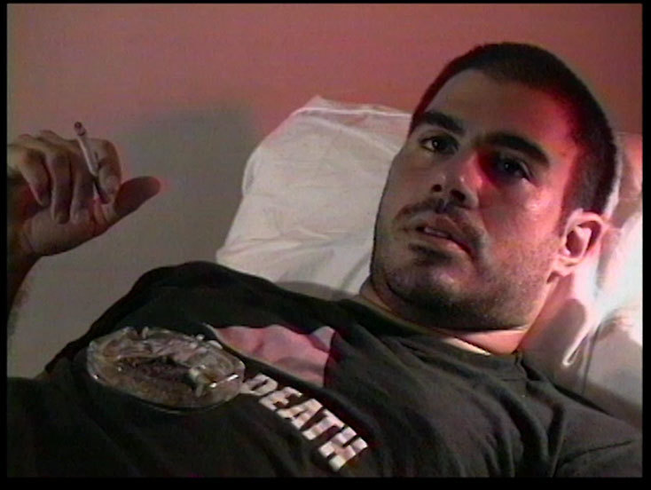 Gregg Bordowitz smokes, staring off into the distance.